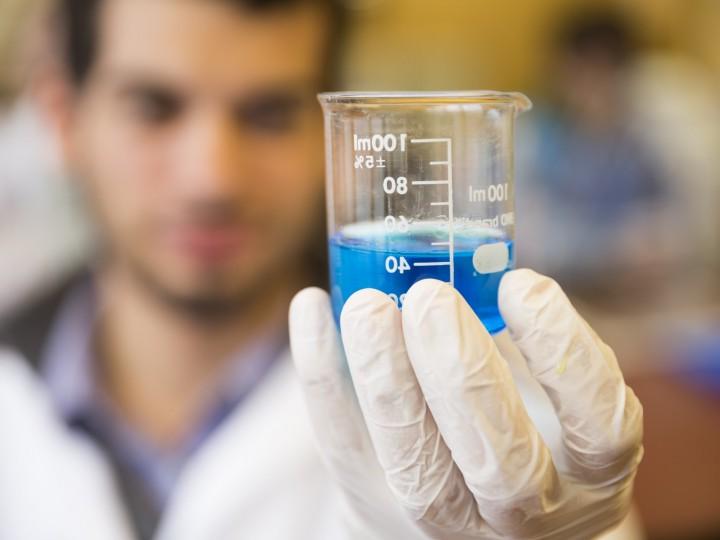 Close up of student holding a beaker filled with blue liquid